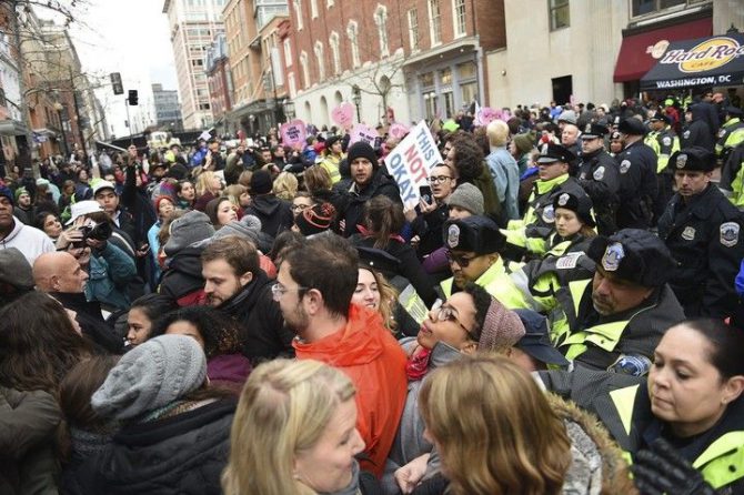 La policía ayuda a varias personas que trataban de asisitir al desfile de investidura y que han sido bloqueados por los manifestantes ubicados en la avenida Pennsylvania, en protesta contra el presidente de Estados Unidos.