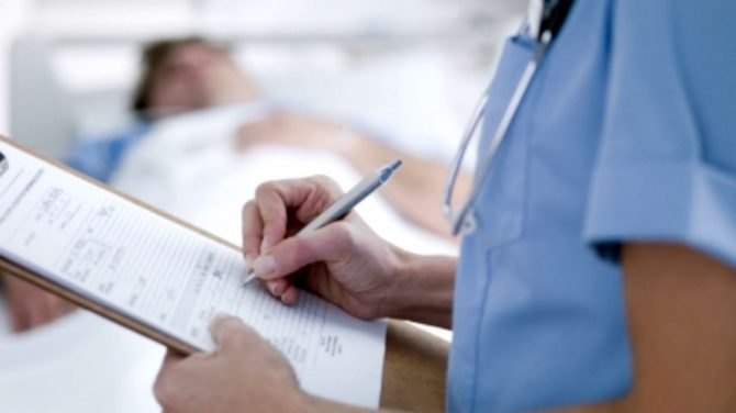 Una enfermera toma nota de los datos de un paciente en un hospital.