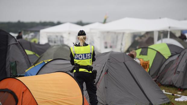 Una policía sueca vigila el lugar donde acampan muchos de los jóvenes asistentes al festival de música.