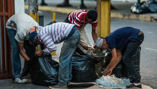Un grupo de personas hurga la basura en busca de comida en las calles de Caracas.