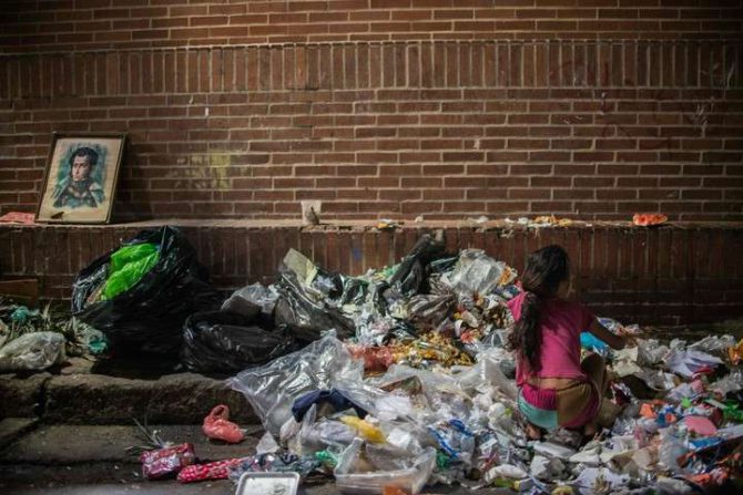 Una nina busca algo que comer entre la basura en Caracas.