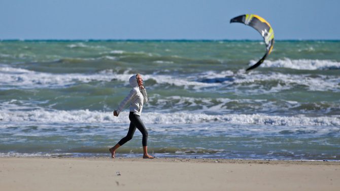 Una mujer camina por una playa de Rímini