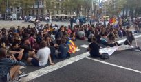 Estudiantes se sientan en la calzada de la Gran Vía de Barcelona para cortar el tráfico.