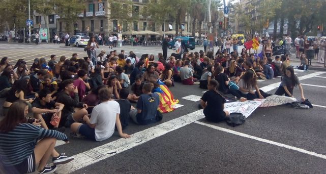 Estudiantes se sientan en la calzada de la Gran Vía de Barcelona para cortar el tráfico.
