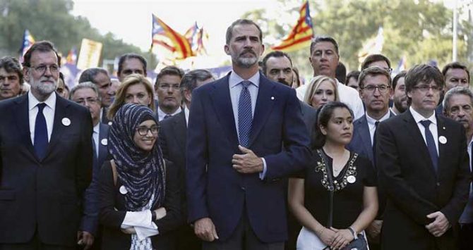 El presidente español Mariano Rajoy, el rey Felipe VI y el presidente catalán Carles Puigdemont, en la cabecera de la manifestación de Barcelona contra el terrorismo, con banderas independentistas al fondo 