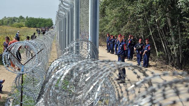 Un grupo de refugiados pasa frente al muro levantado por Hungría para impedir la llegada de inmigrantes