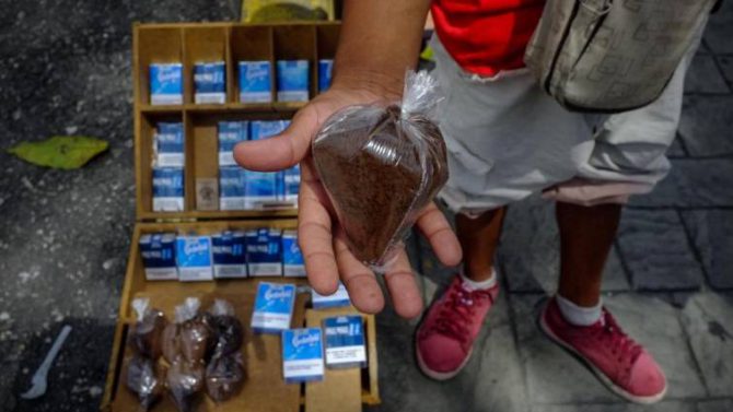 Un vendedor sostiene una bolsa de café en un puesto de venta informal en una calle de Caracas (Venezuela)