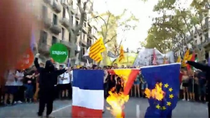 Catalanes queman las banderas de Francia, España y la Unión Europea.