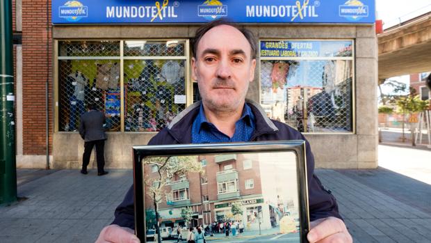 El comerciante José Luis Muñoz, delante de su tienda ya rotulada como «Mundo textil» sostiene una fotografía del establecimiento con su anterior nombre (ABC)