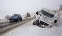 Un coche circula por una carretera del paso fronterizo del Portalet entre España y Francia cubierta por la nieve caída en la zona.