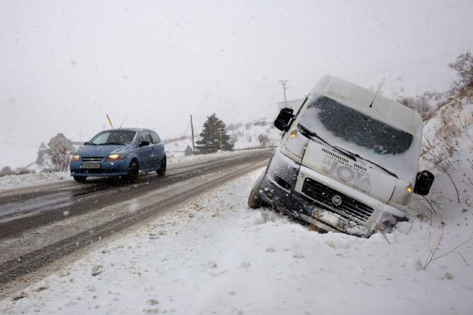 Un coche circula por una carretera del paso fronterizo del Portalet entre España y Francia cubierta por la nieve caída en la zona.