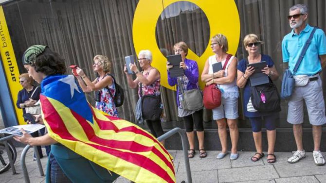 Turistas fotografían a un ciudadano que pasea envuelto en una estelada