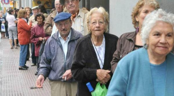 Pensionistas españoles hacen cola para cobrar.