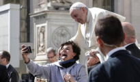 El Papa Francisco posa para un selfie con una joven a su llegada a la audiencia general de los miércoles en la plaza de San Pedro del Vaticano