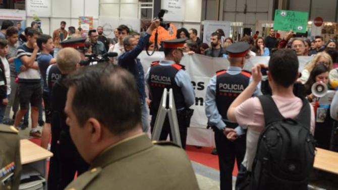 Los miembros de la plataforma Desmilitaricemos la Educación ante el «stand» de los militares