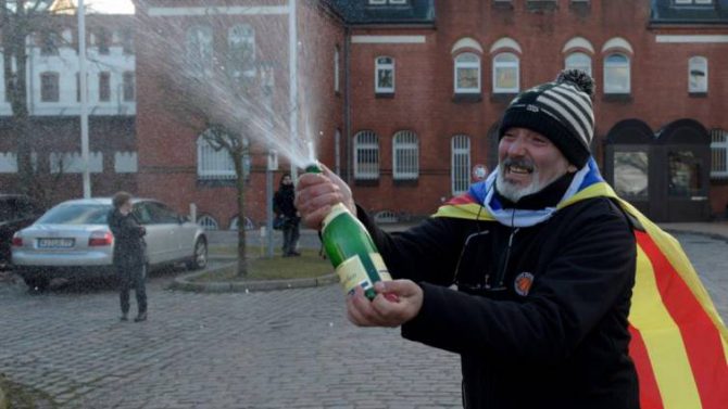 Un hombre con una estelada celebra con champán frente la cárcel de Neumünster, la decisión de la justicia alemana. 