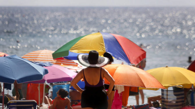 Varios turistas disfrutan del sol y el agua en la playa de Levante de Benidorm. 