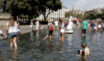 Unos turistas se bañan en la plaza Cataluña de Barcelona