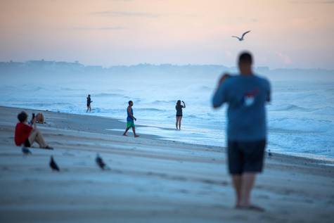 Varias personas toman fotografías al amanecer en una playa de Carolina del Norte.