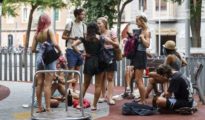 Varios turistas beben cerveza entre los columpios para niños de la plaza del mercado del barrio (La Vanguardia)