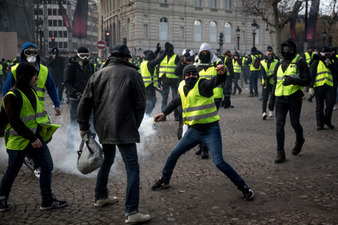 París, 8 de diciembre de 2018: un manifestante lanza un bote de gas lacrimógeno contra la policía durante una manifestación de los 'chalecos amarillos' en las inmediaciones del Arco del Triunfo.