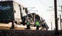 Varios operarios pasan junto un tren de carga en el puentoe Gran Belt en Nyborg (Dinamarca), tras registrarse el accidente ferroviario