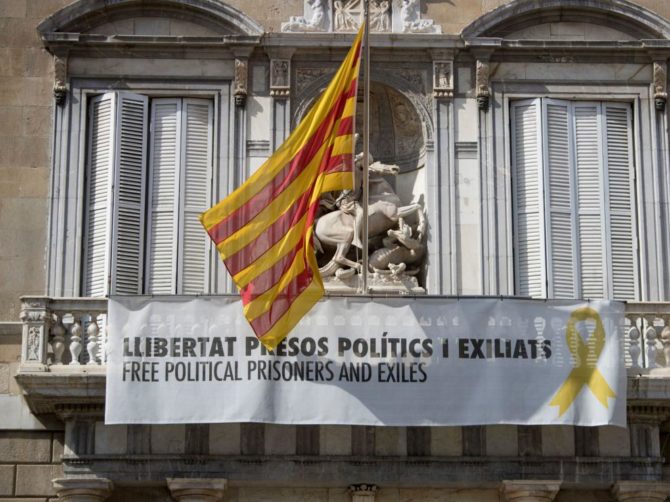 Fachada de la Generalitat, donde cuelga un cartel y un lazo amarillo reivindicando la libertad de los políticos presos.