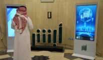 Un empleado del Ministerio del Interior del Gobierno saudí frente al logo de la aplicación Absher. Riad, Arabia Saudita. 19 de febrero de 2019 (RT)
