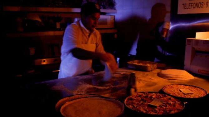 Un cocinero hace pizza iluminado por velas en Caracas 
