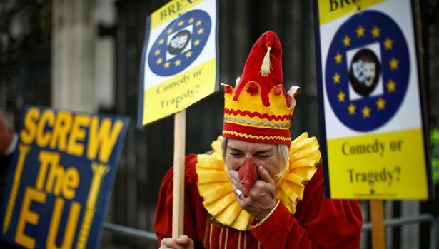 Un partidario de la UE vestido de bufón junto a un cartel de manifestantes anti-UE
