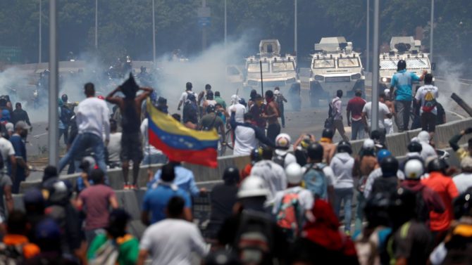 Grupos de manifestantes se enfrentan a las tanquetas de las fuerzas bolivarianas en la proximidades de la base aérea de La Carlota